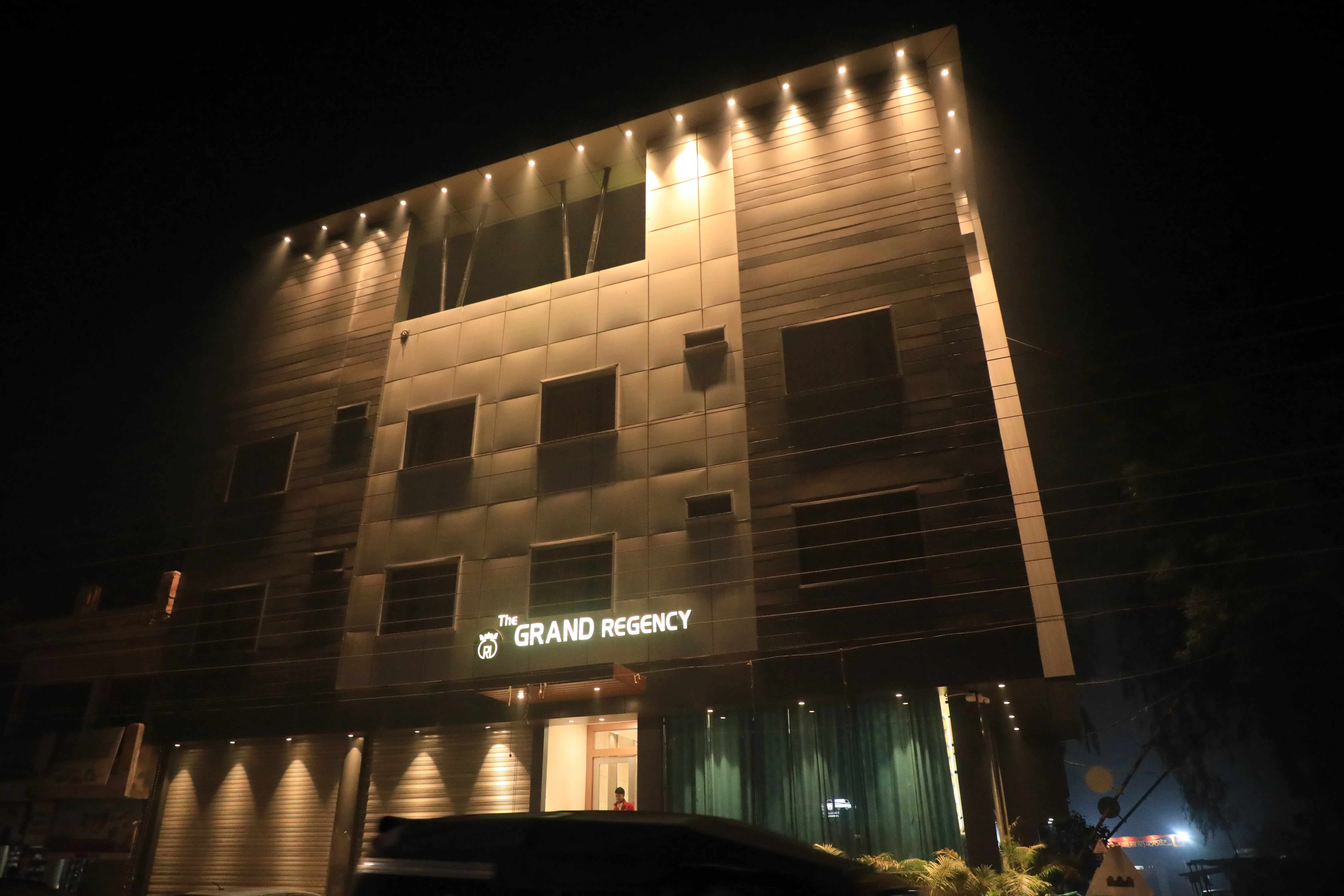 Exterior evening view of The Grand Regency Pathankot illuminated in gold